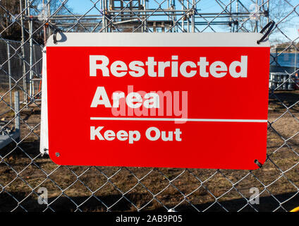 Restricted Area Keep Out red and white sign on fence at construction site. Stock Photo