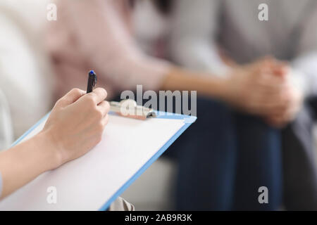 Psychologist writing in blank notepad at family counseling session Stock Photo
