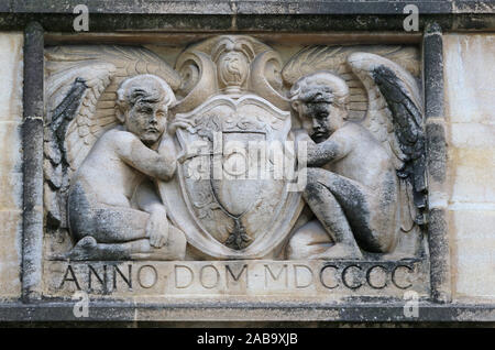 stone carving on a wall in St John's college Oxford part of the university showing two angels or cherubs and the coat of arms of the college from 1900 Stock Photo