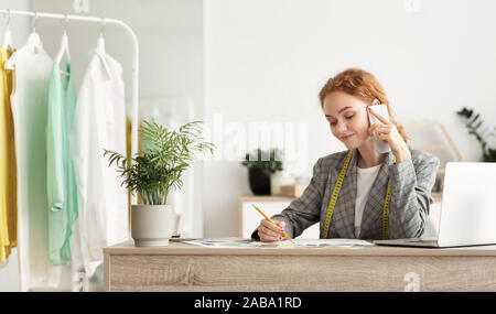 Young fashion designer discussing customer's order on phone Stock Photo