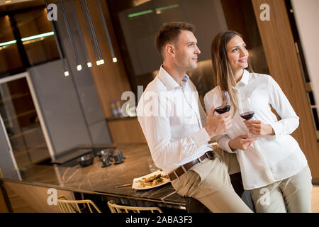 Sweet young couple drinking red wine after romantic dinner at luxury kitchen Stock Photo