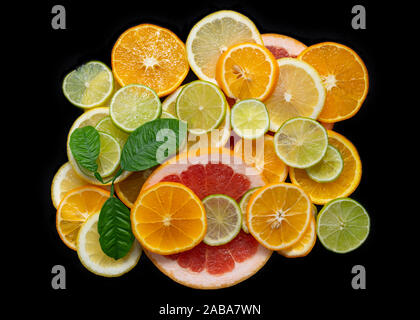 Sliced citrus fruits isolated on a black background close-up, top view. Juicy ripe orange, tangerine, grapefruit, lime and lemon macro. Fruit mix. Stock Photo