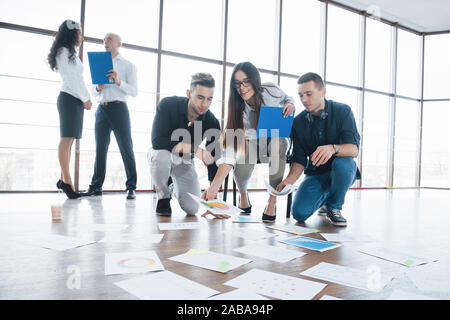 Planning strategy together. Business team looking at papers on floor in search of one idea. Cooperation corporate achievement and teamwork concept Stock Photo