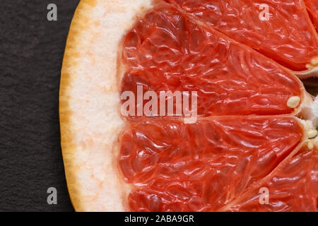 Sliced red grapefruit on black background closeup. Food background. Flat lay. Juicy ripe fresh citrus fruit grapefruit. Top view, macro. Stock Photo