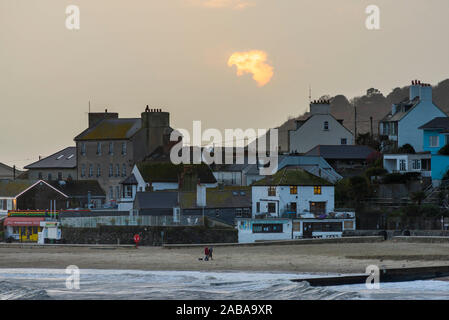Lyme Regis, Dorset, UK. 26th Nov, 2019. UK Weather. The sun partially obscured by heavy clouds above the seafront at sunset at Lyme Regis in Dorset at the end of an overcast and stormy day. Picture Credit: Graham Hunt/Alamy Live News Stock Photo