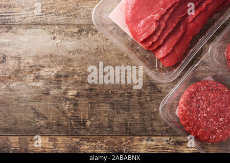 Different types of meat packaged in plastic on wooden table. Top view Stock Photo