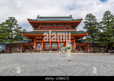 Two young Asian tourists dressed in traditional japanese kimonos taking a photo in front of the famous Heian Shrine in Kyoto, Japan.