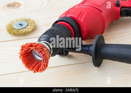 Red drill and abrasive brushes with nylon and metal wire on a wooden surface. Tools for cleaning, polishing and grinding of wood and metal. Front view Stock Photo
