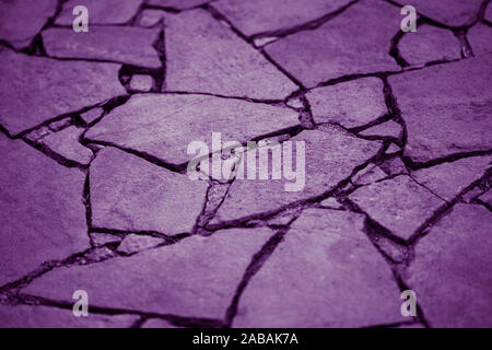 Road surface made of natural wild stones, violet tone. Stock Photo