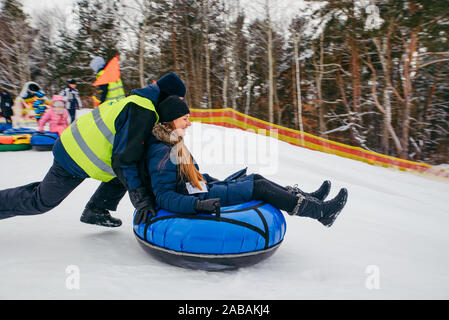 young woman preparing to slide down by hill on snow tube Stock Photo