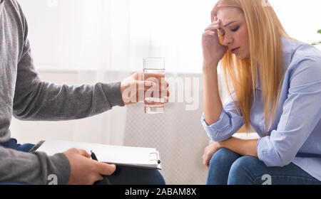 Psychotherapist offering glass of water to depressed woman Stock Photo