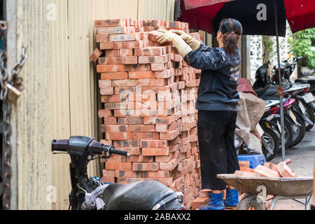 A asian woman piles bricks up on a construction site in Hanoi, Vietnam, Asia ready for construction work Stock Photo