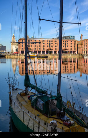 Tall shot of the Albert Dock in Liverpool through the rigging of a small boat moored at the side Stock Photo