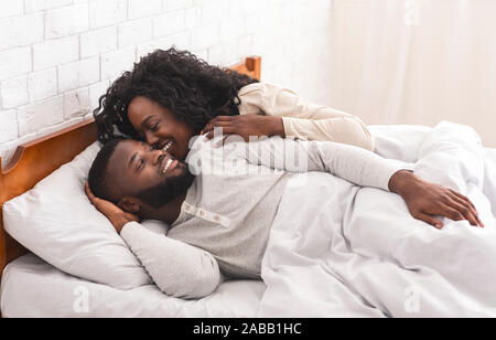 Loving black couple having fun in bed, kissing and hugging Stock Photo