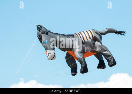 a kite in the shape of a donkey flying high in the sky on a windy day Stock Photo