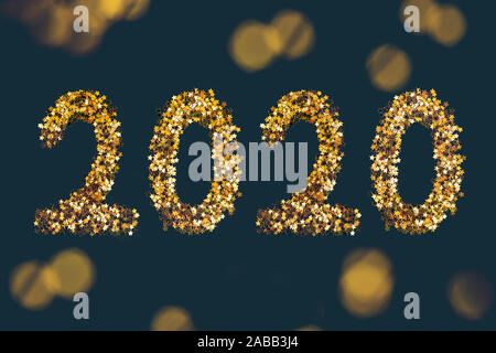 Golden stars sparkles shaped 2020 on dark background. Stock Photo