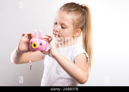 Little girl with a pink camera in hands on a white background Stock Photo