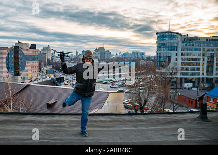 Young happy hipster man with drone in hands on the roof. Stock Photo