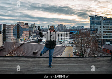 Young happy hipster man with drone in hands on the roof. Stock Photo