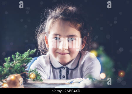 Cute caucasian girl with christmas gingerbread cookies. Christmas portrait in dark key lighting Stock Photo