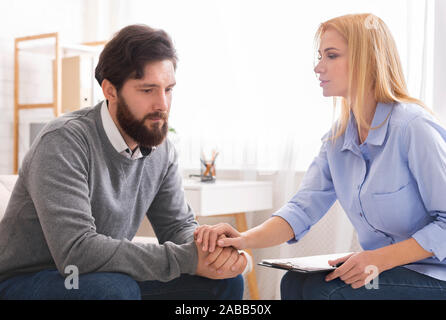 Psychologist comforting depressed man patient at consultation Stock Photo