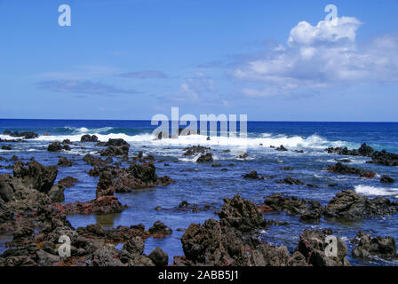 Blue ocean (sea) and white waves breaking on rocks on the rocky shoreline of Easter Island. Stock Photo