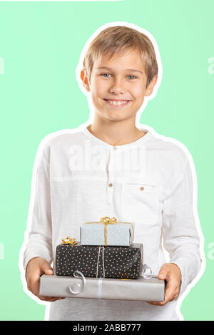 Happy boy holding stack paper wrapped present gift boxes. Magazine collage style with light green color background. Holidays, Christmas concept Stock Photo
