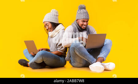 Friendly african couple using laptops, sitting on floor Stock Photo