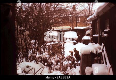 Vintage cars snowy winters garden scene - photo taken late 1960's to early 1970's. Stock Photo