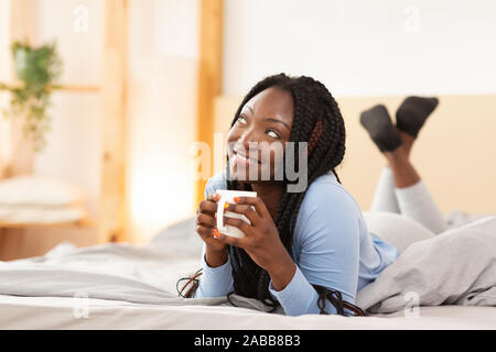 Happy African American Woman Having Coffee Lying In Bed Indoor Stock Photo