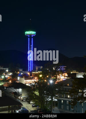 Gatlinburg Space Needle illuminated with neon, vibrant downtown bustling with tourists, Great Smoky Mountains National Park in distance, Tennesse, USA Stock Photo