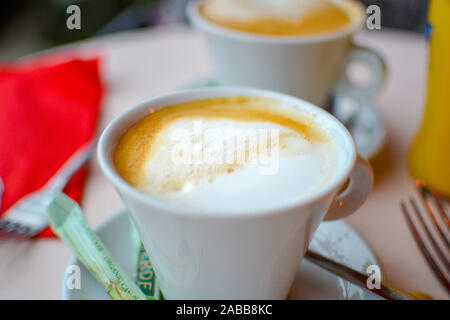 Close up of a table setting with two cups of coffee or cappuccino with milk froth on top. Stock Photo