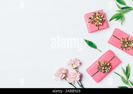 Festive floral background of pink flowers and gift boxes on white table with copy space, flat lay. Stock Photo