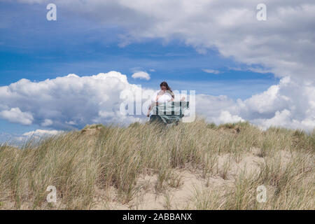 Woman standing on a sand dune on a windy day, Benar Beach, Barmouth, Gwynedd, Wales, UK Stock Photo