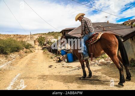 An old cowboy named Ruben Arviuzu Reyes prepares his horse by placing the Saddle in the Pilares village of Nacozari. Ruben takes care of the old constructions of the ghost town which is also a tourist town or abandoned mining town. Pilares, is a city in the municipality of Nacozari de García, Sonora, Mexico, in the upper area of the Sierra Madre Occidental. Since 1960 it is known as a ghost town due to its depopulation in the 1920s, due to the closure and elimination of the mining companies that were here and that gave rise to it. © © (© Photo: LuisGutierrez NortePhoto.com)  un viejo vaquero d Stock Photo