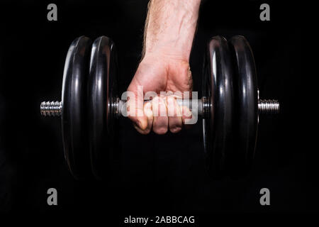 Male hand holds a metal bar on a black background Stock Photo