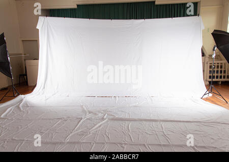 Pull back of set up for professional photography shoot. Volume portrait session. White muslin backdrop 6 metres wide by 3 meters long. Floor covered Stock Photo
