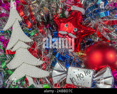White Christmas tree and ornaments on multicolored tinsel in background, photo-illustration Stock Photo