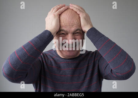 Senior hispanic man laughing out loud with closed eyes and hand on his head. Positive facial human emotion. Studio shot Stock Photo