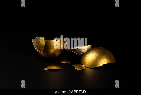 broken Golden egg, Golden shell lying on a black background Stock Photo