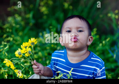 A young toddler holding a bouquet of California wildflowers, with puckered lips giving kisses. Stock Photo