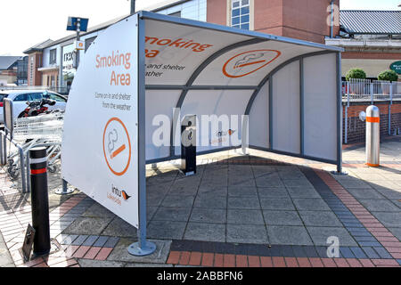 Intu Properties provide smokers a smoking area cubicle shelter at entrance to shopping mall Thurrock Lakeside indoor shopping centre Essex England UK Stock Photo