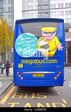 Back view of Megabus.com low cost intercity bus travel people at bus stop in Newcastle advertising for its links with Silverstone circuit England UK Stock Photo