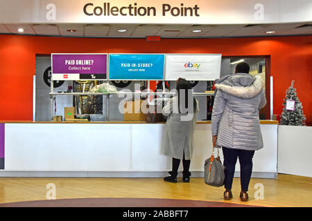 Interior of retail business at Argos catalogue shopping store back view of customers being served at collection point counter at Christmas England UK Stock Photo