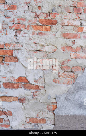 Old weathered red brick wall fragment, crumbling plaster Stock Photo