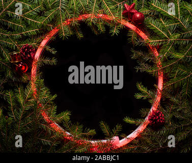 Christmas round frame made by neon and winter things on black background. Stock Photo