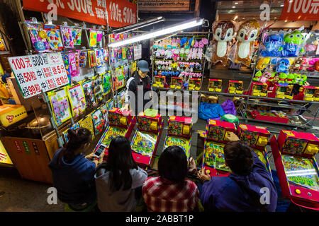 Taoyuan, Taiwan - November 12, 2019: A group of young Taiwanese people playing games at a game stall located in Zhongli Night Market in Taoyuan, Taiwa Stock Photo