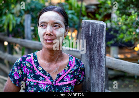 Young Burmese village woman with her face and neck painted with thanaka, a natural cosmetic and sunscreen on the Chindwin River, Myanmar (Burma) Stock Photo