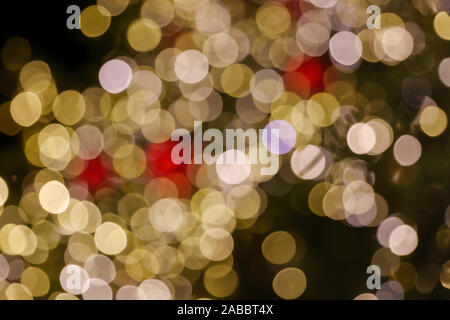 Gold and red Christmas light shiny abstract round bokeh on black background. Colourful Glitter bokeh from blurry decoration bulbs. Stock Photo