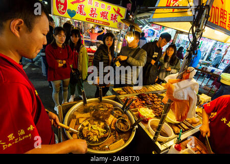 Taoyuan, Taiwan - November 12, 2019: Vendor working and preparing food in a street food stall at the Zhongli Night Market located in Taoyuan, Taiwan. Stock Photo